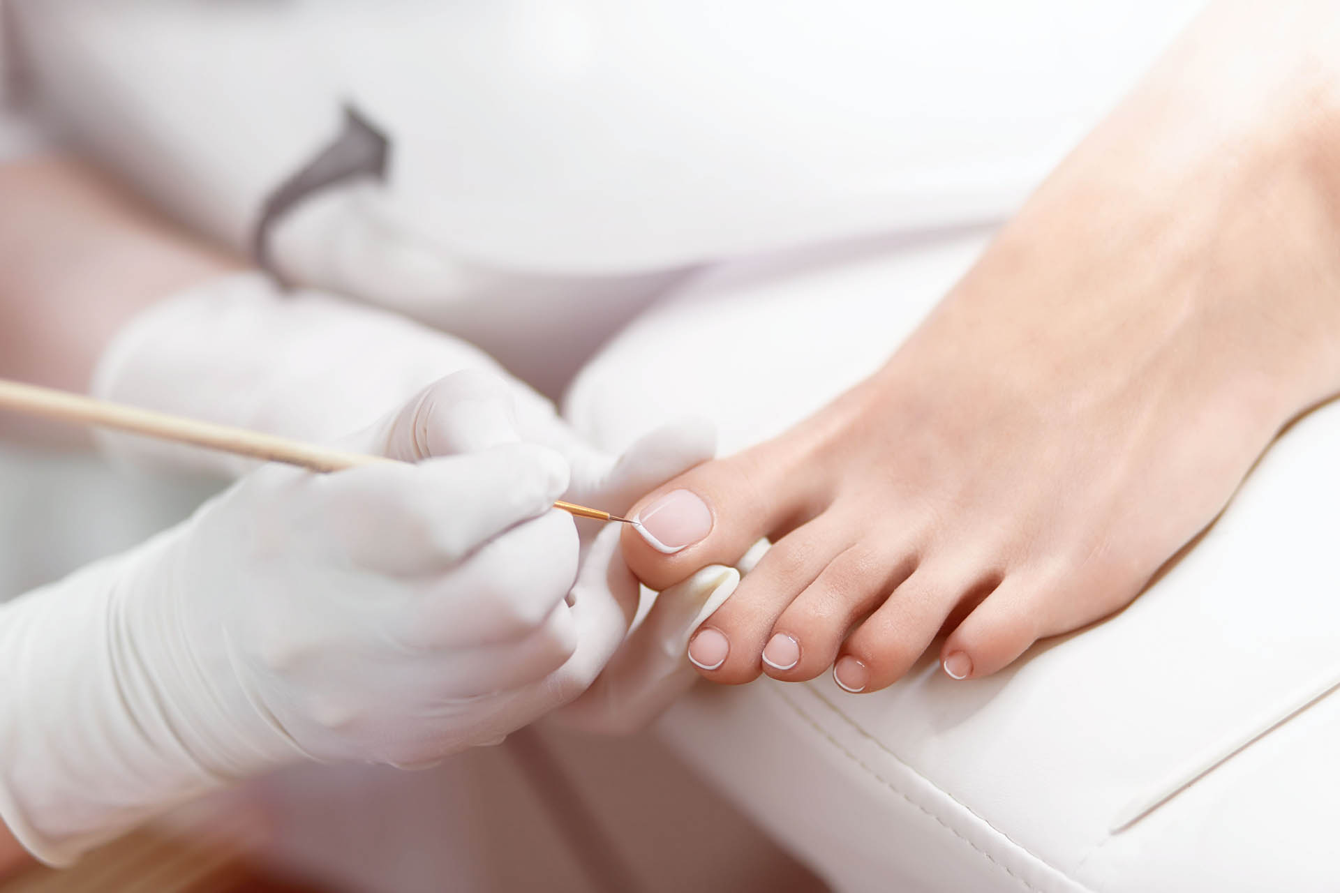 Specialist in beauty salon making french pedicure for female cli